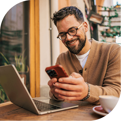 Human with glasses laughing while watching something on his phone